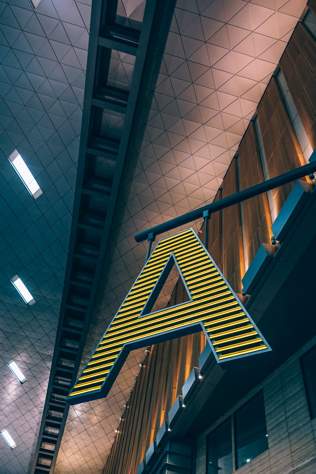 An airport departures hall, empty check-in desks under a high ceiling and long horizontal signage.