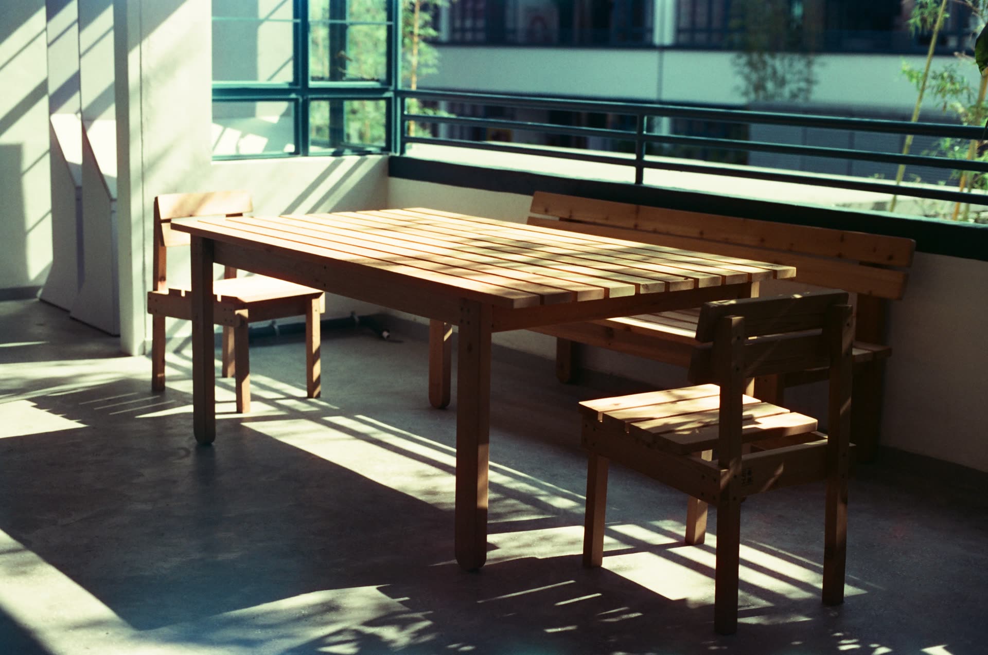 Bare furniture in an empty room, hard afternoon light throwing long shadows across the floor.