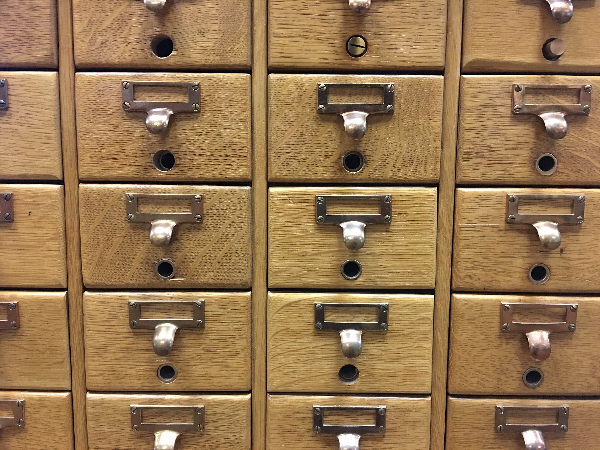 A wooden card catalogue, drawers closed, index labels on each front.