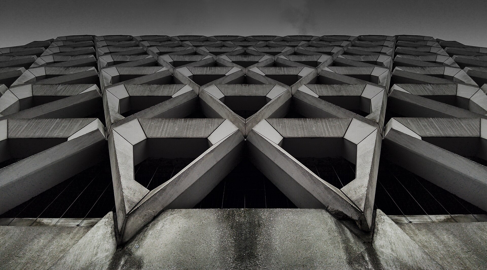 A concrete facade of repeating cast bays, photographed from directly below.