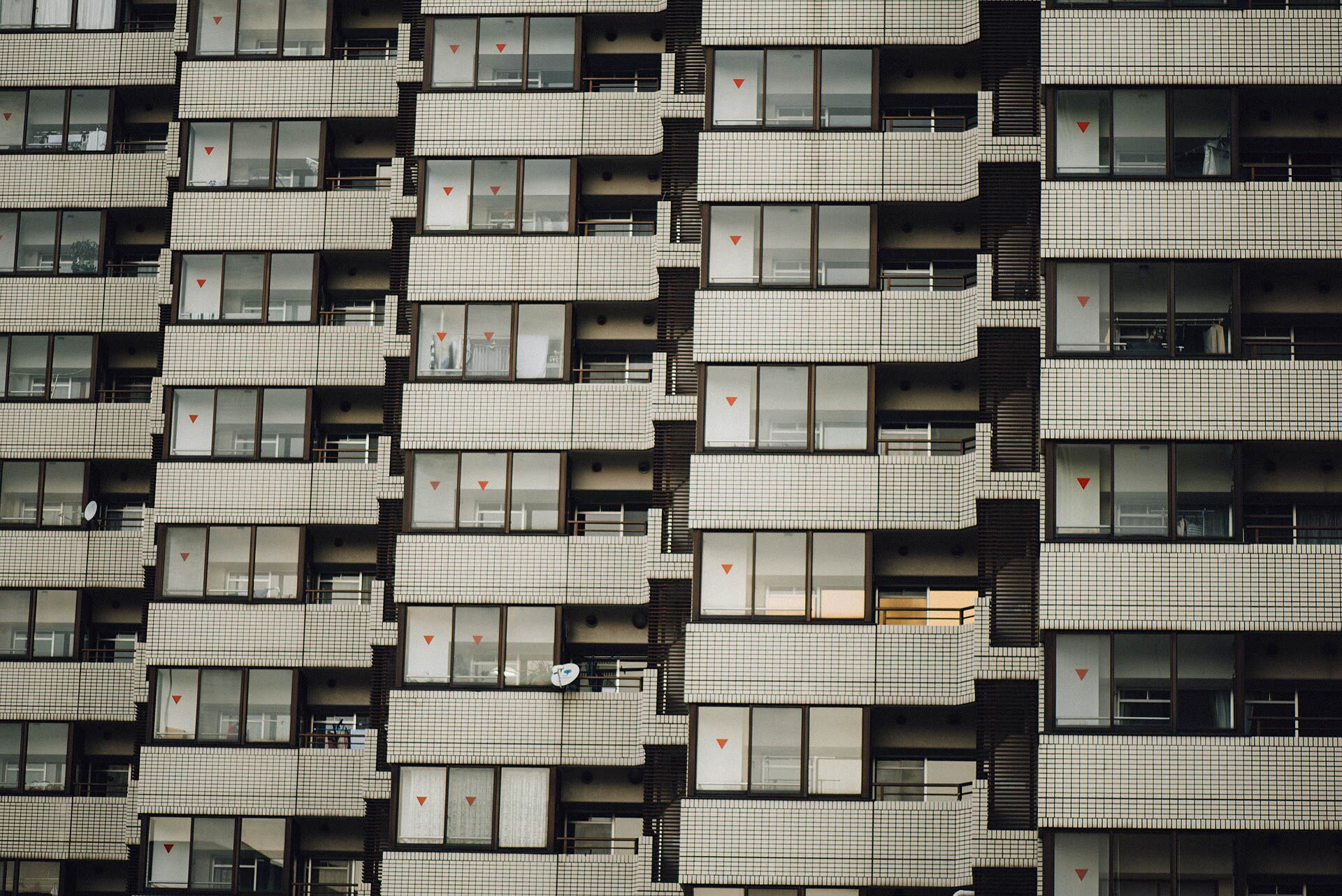 A tiled apartment block filling the frame, ranks of identical balconies and windows stacked without a break.