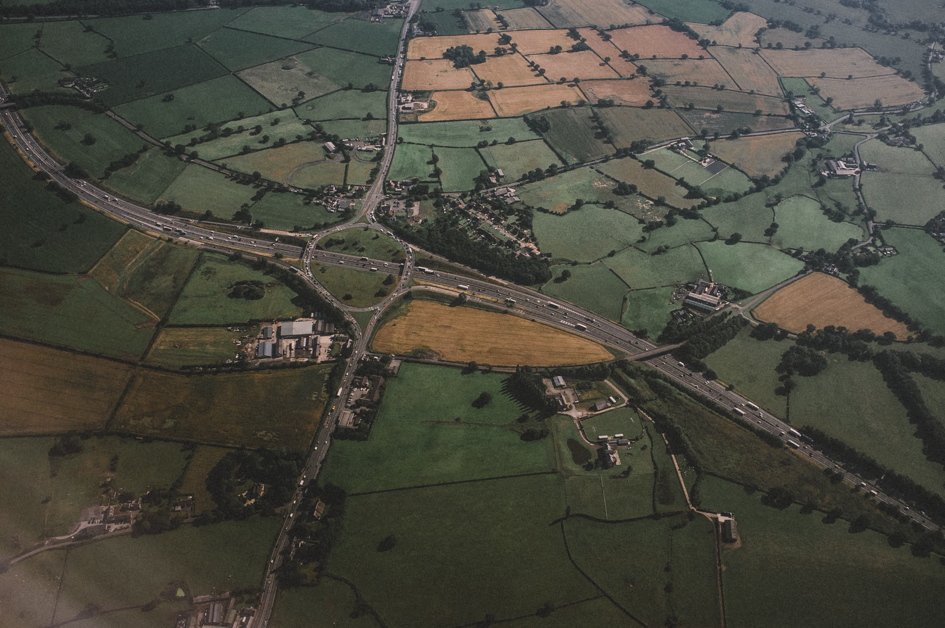 A motorway junction seen from above, carriageways and slip roads curving through open ground.