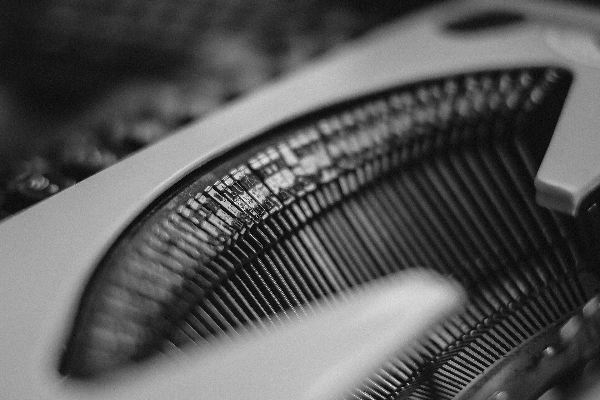 A monochrome close view of a typewriter's typebars, the ranked slugs curving away out of focus.