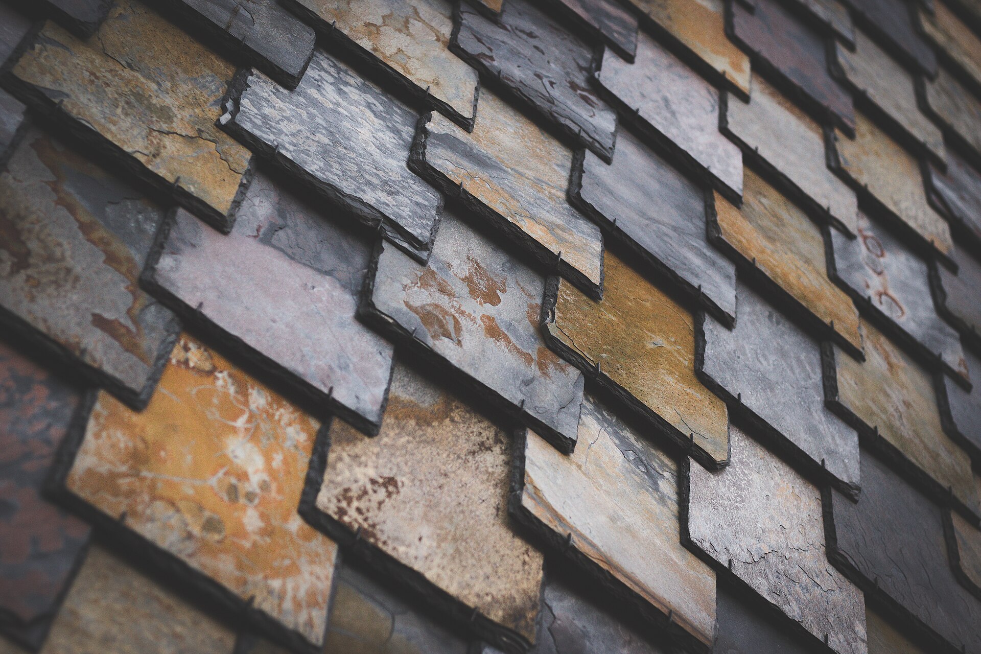 Overlapping split-stone shingles on a wall, each course laid over the last, no two pieces alike.